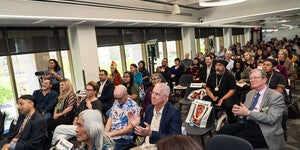 A large crowd of people seated in the Labriola Center from the front all the way to the back wall with Labriola family and Simon Ortiz seated in front