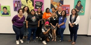 A group of people standing in front of a colorful art wall smiling for the camera