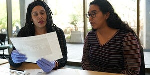 Two people sitting next to each other at a table looking at archival materials