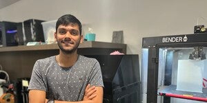 Student standing next to 3D printers in the Makerspace