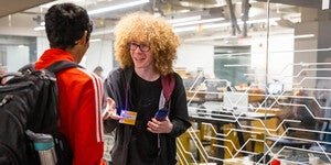 Male student staff greeting a student visitor outside the Makerspace.