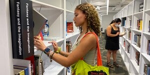 Two people in the library browsing books on the shelves