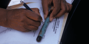 Close up of male hands writing on a blood sample cylinder from the Tuskegee Syphilis Study NIAD: 824613