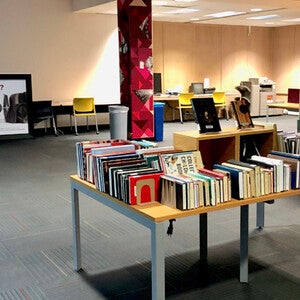 A sign describing the collection, books arranged on a display table, and a second bookshelf with more books.