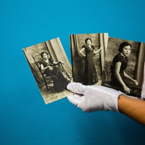 An archivist displays old photographs that are part of a community-driven collection. Links to an article about the project.