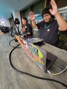 Two Indigenous male deejays sitting behind their equipment.