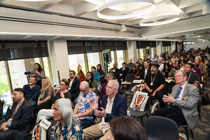 A large crowd of people seated in the Labriola Center from the front all the way to the back wall with Labriola family and Simon Ortiz seated in front