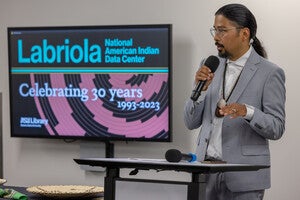 Director Alex Soto speaking in front of audience with sign behind him that says "Celebrating 30 Years 1993-2023"