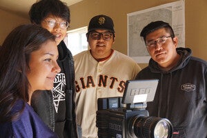 Four people around a film camera