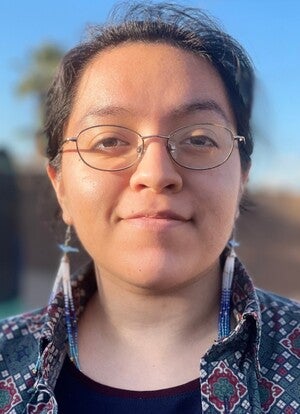 Elena Dominguez smiling wearing beaded earrings and glasses