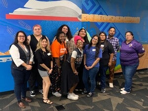 A group of people standing in front of the Labriola Center mural at Hayden Library