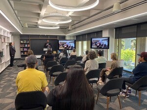 Photo of Dr. Jerome Clark at the front of the room introducing Dr. Valerie Lambert, standing to the left. 