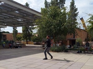 Male dancer performing on tile concrete during the day.