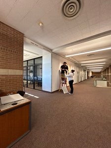 Photo of Nataani Hanley-Moraga and Mafi Pamaka setting up the display on the third floor of Fletcher library.