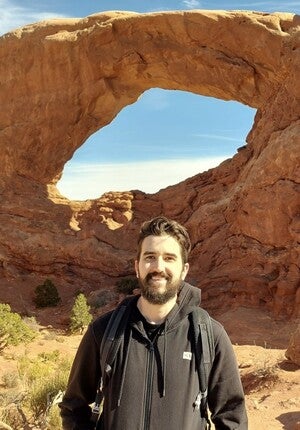 a male standing in front of a rock formation