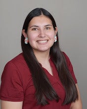 Portrait of Baylee LaCompte wearing beaded earrings and a maroon shirt. 