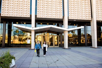 Two people walking outside of Hayden Library