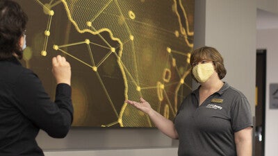 Librarians talking in front of digital map display