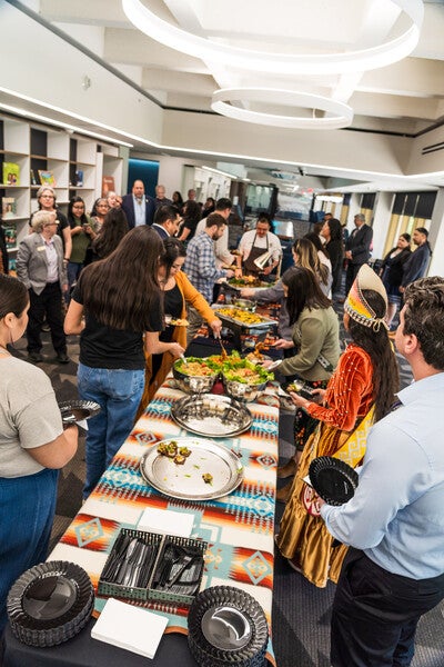 People lined up alongside a long table with Chef Nephi at the end serving bison