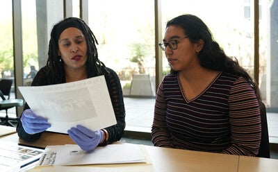 Two people sitting next to each other at a table looking at archival materials