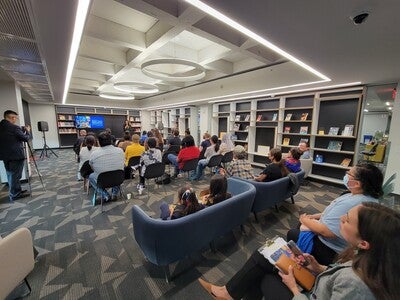 A seated group of people watch a speaker presenting at the book awards.